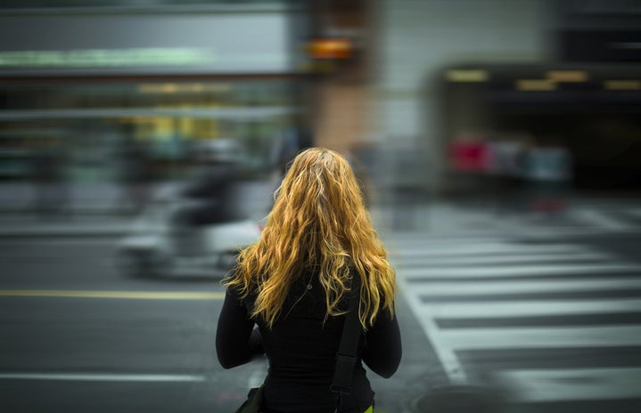 woman standing facing blurry street