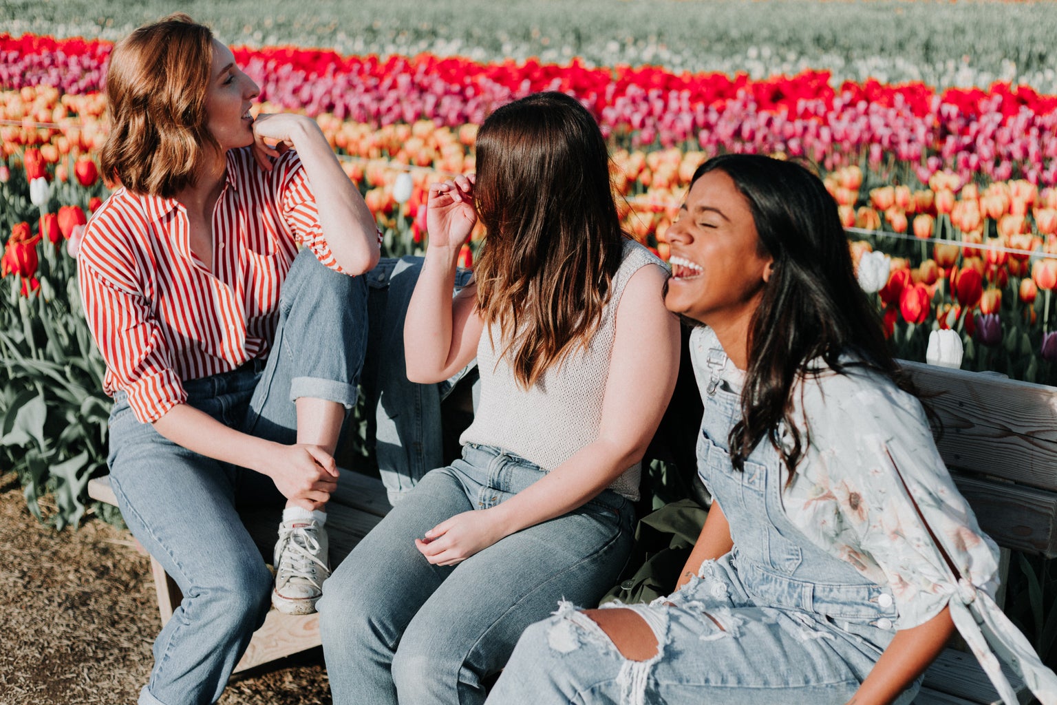 Women laughing together on a bench in front of tulips