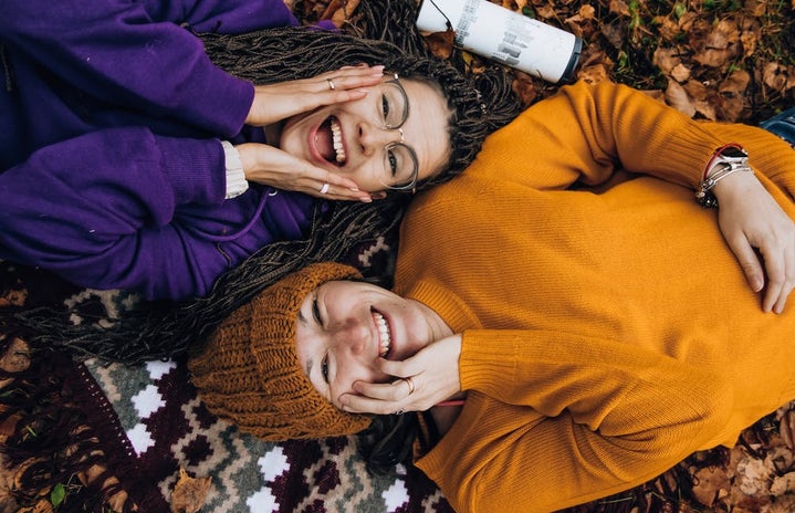 Two women laughing and laying in leaves