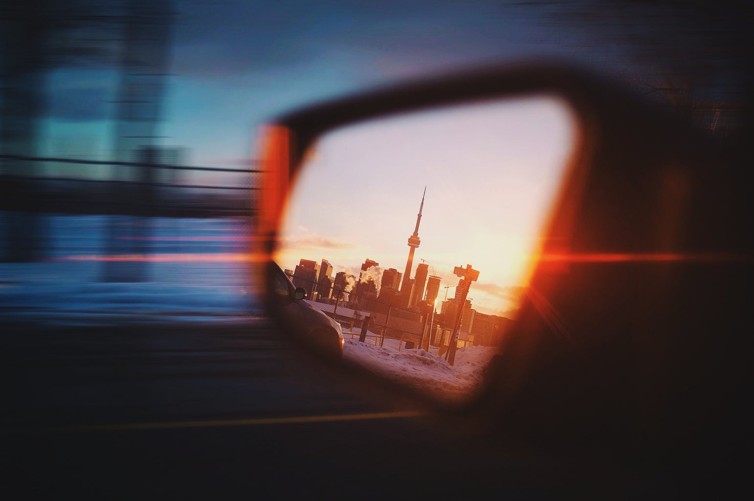 CN tower reflection in sideview mirror of moving vehicle