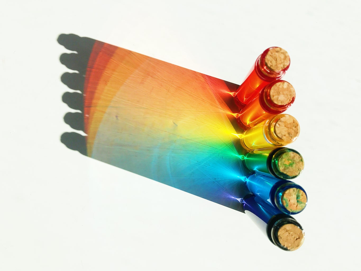 light shining through 6 different colored glass bottles to form a rainbow