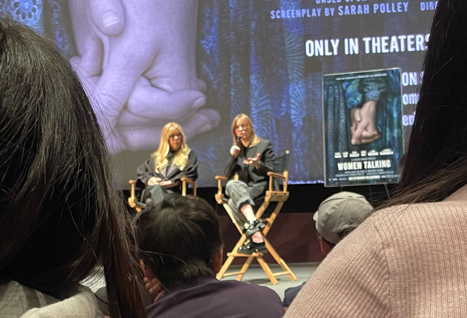 Two women in director\'s chairs on a stage discussing the film Women Talking.