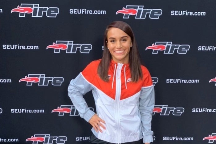 girl with red and white track jacket, posing and smiling.