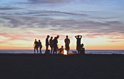 Friends around a campfire by the beach at sunset