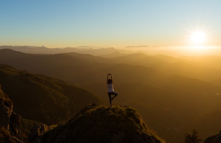 Woman stretching on Mountain Top During Sunrise