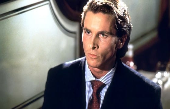 Christian Bale as Patrick Bateman in the movie American Psycho sitting on a couch