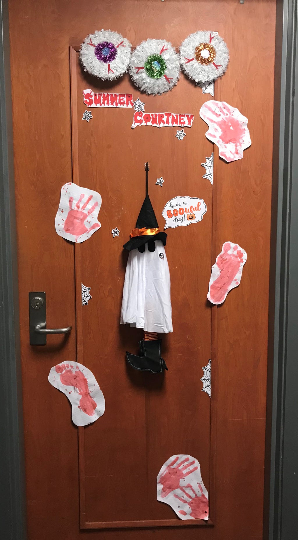 3 eyes at the top of a door with hand and footprints all over and a ghost in the middle