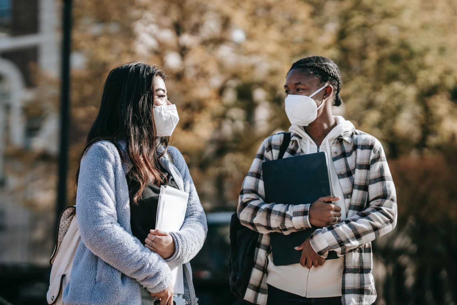 College students with masks walking across campus together.