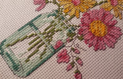A cross stitch of flowers in a mason jar