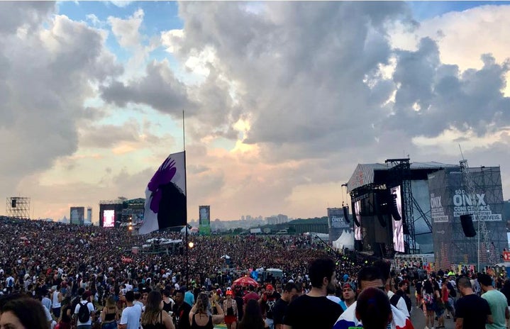 Wide view of two concert stages while the sun sets and the crowd enjoys the live music