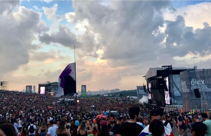 Wide view of two concert stages while the sun sets and the crowd enjoys the live music