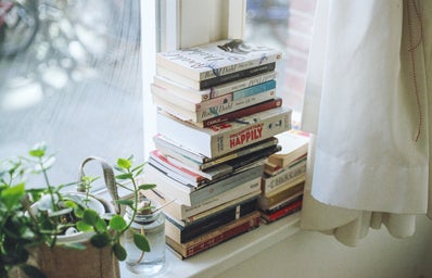a stack of books on a window shelf