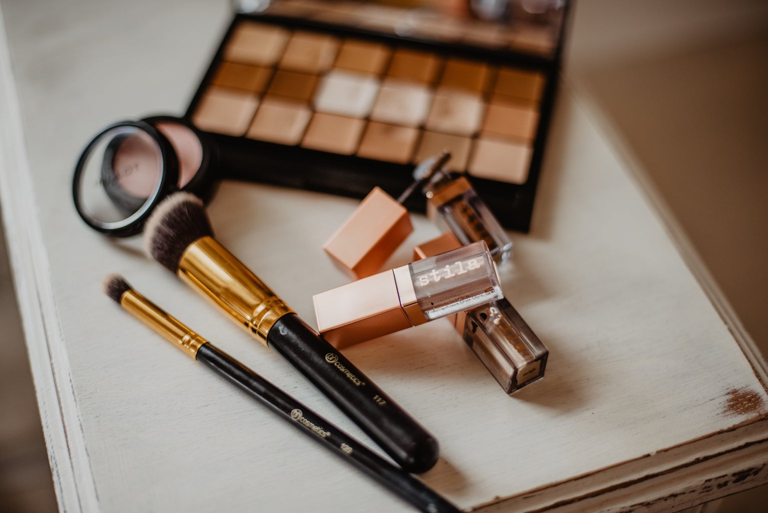 Cosmetics and brushes rest on a table