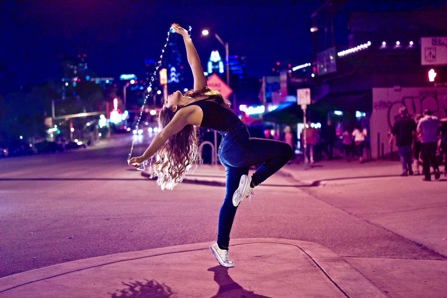 Girl dancing in the street with lights