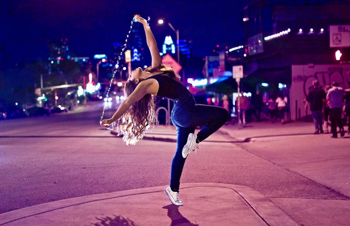 Girl dancing in the street with lights