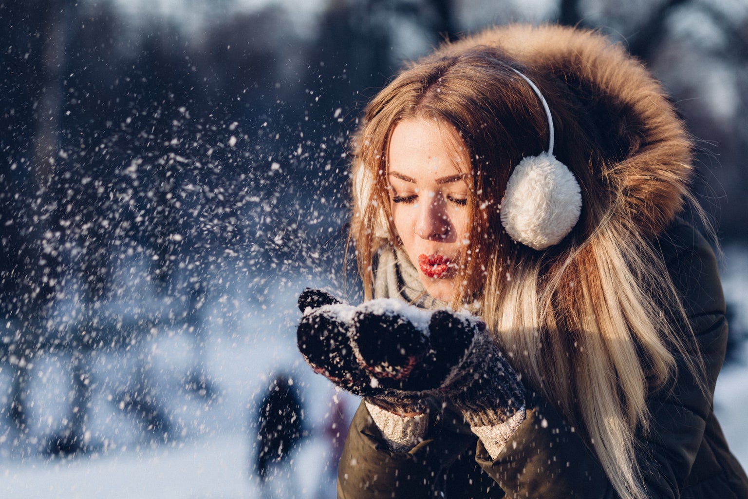Picture of woman wearing white earmuffs blowing snow