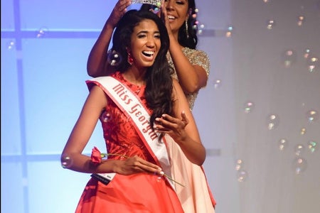 Girl is being crowned as Miss Georgia Teen on a red gown