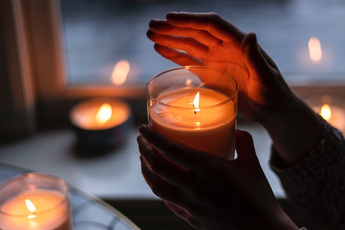 A woman\'s hand holding a burning candle