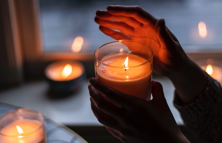 A woman\'s hand holding a burning candle