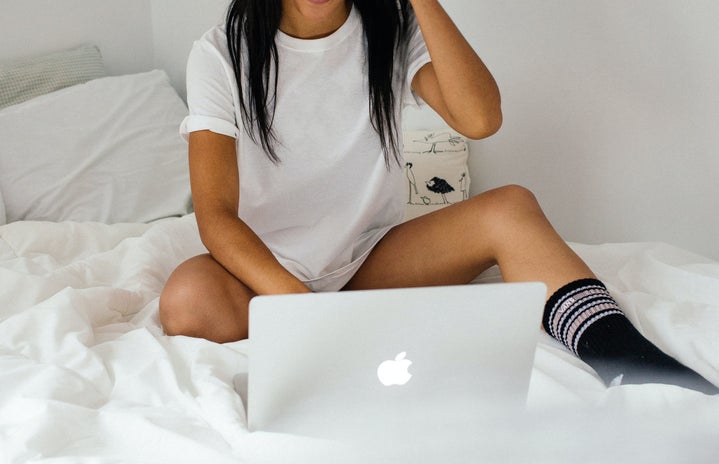 Woman sitting on bed with laptop
