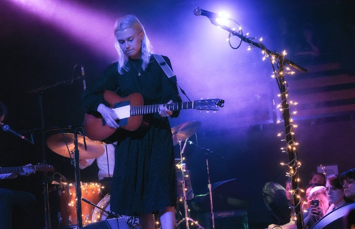 Phoebe Bridgers playing guitar live in concert