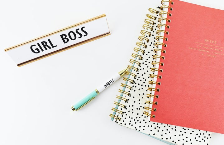 desk with notebooks and "girl boss" plaque on it