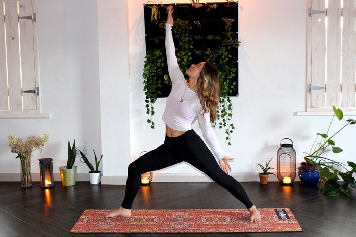 Woman doing yoga with plants and candles