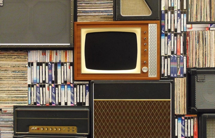 Retro wooden TV, VHS tapes and old stereos surrounding it