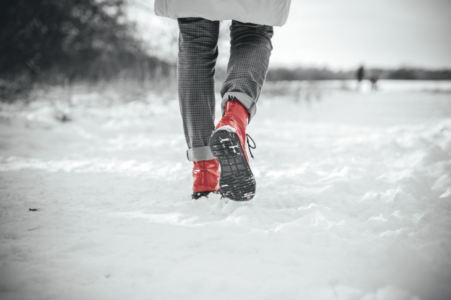 person in grey pants and red sneakers walking in snow