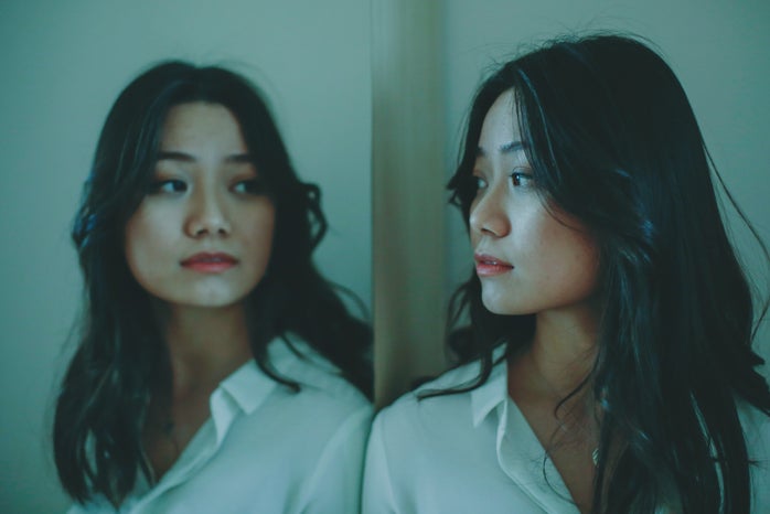 A woman looks at her reflection in the mirror.