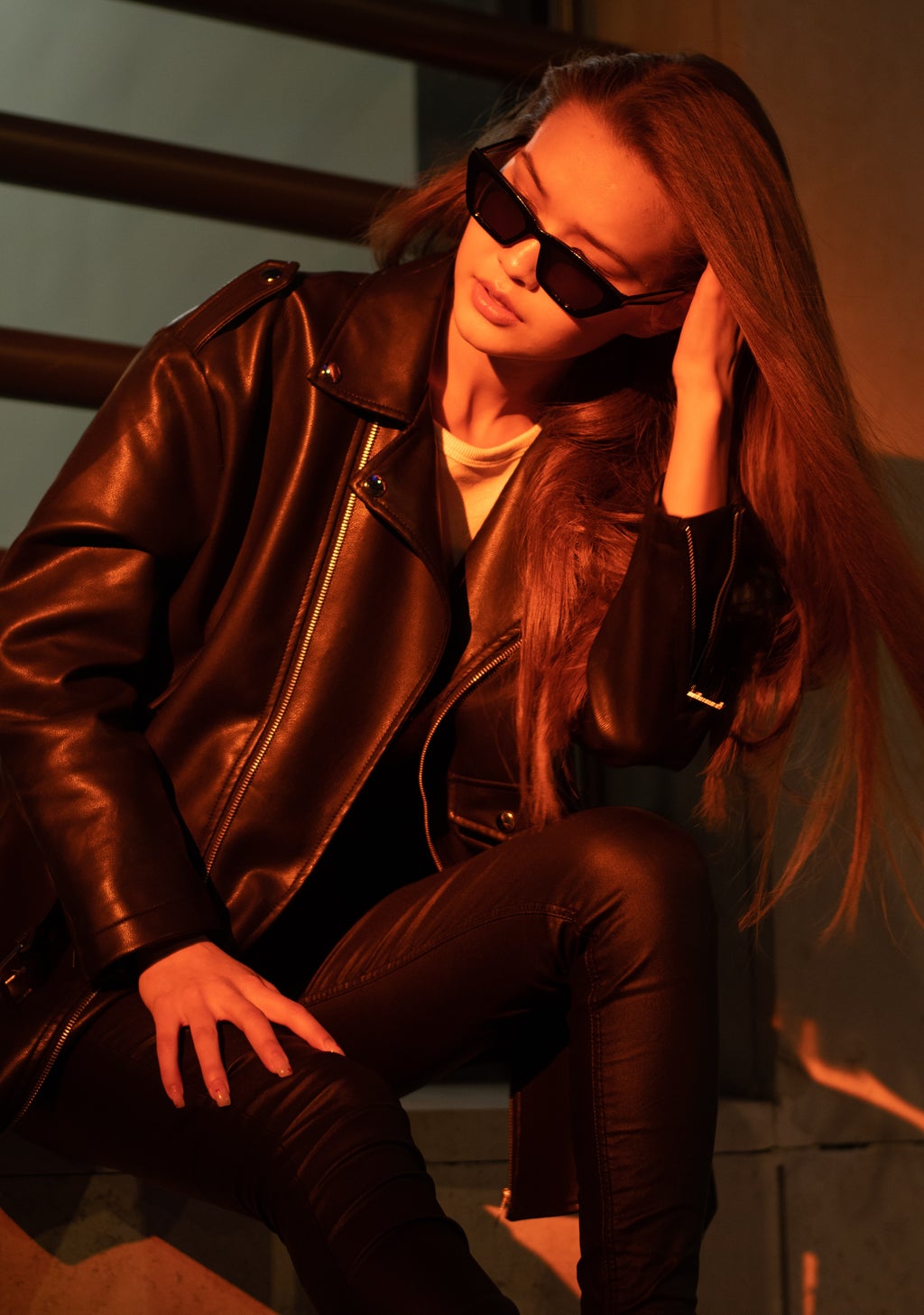 Woman with black sunglasses on and leather jacket.