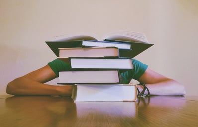 Person hiding behind stack of books.