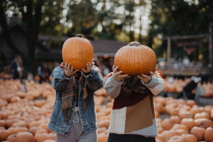 Two women holding pumpkins in front of their faces