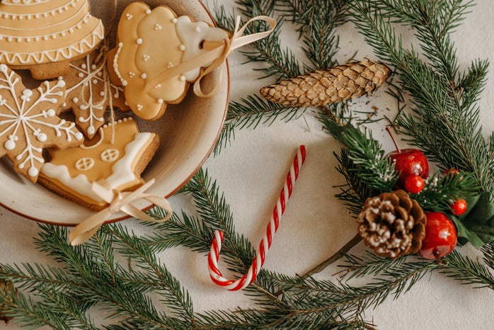 a plate of sugar cookies surrounded by candy canes, pinecones, and green.