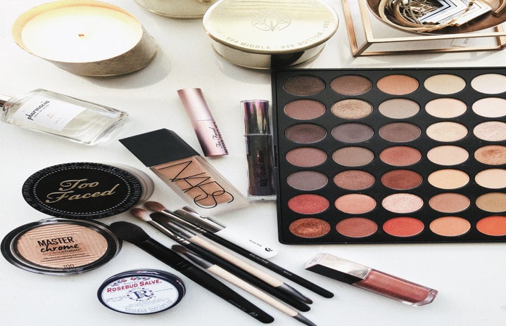 makeup products and candles laying on a table