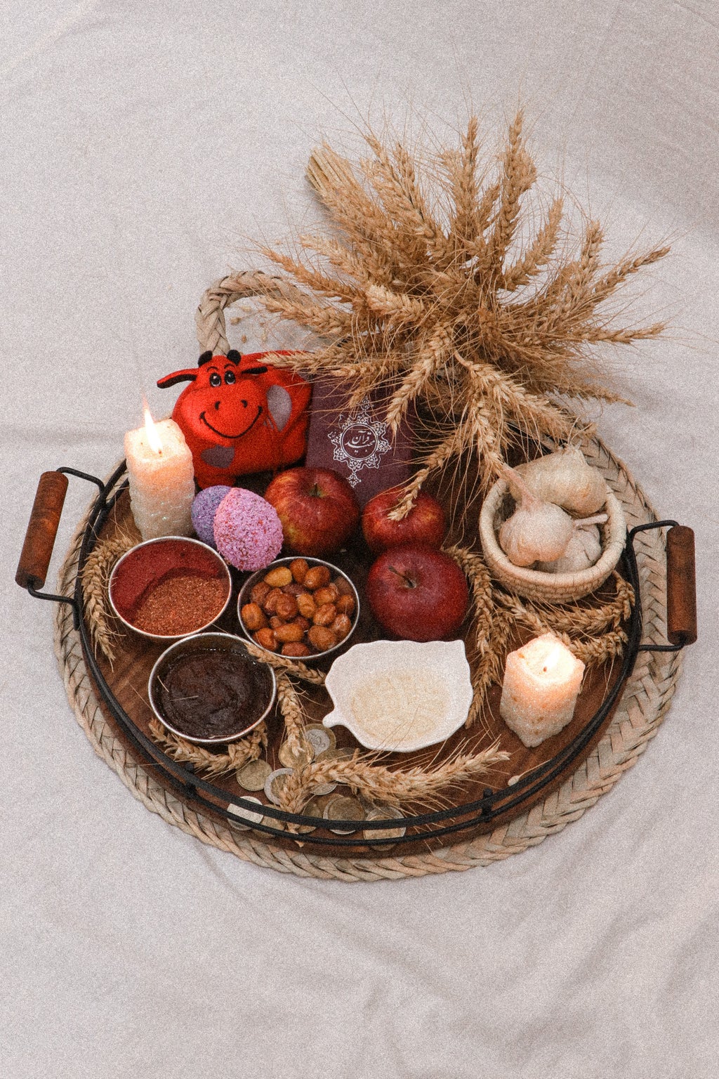 Red apples, lit candles, food, and other elements in a woven basket