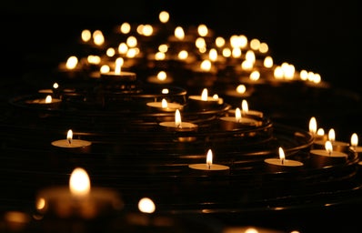A collection of candles that are lit up against a black background.