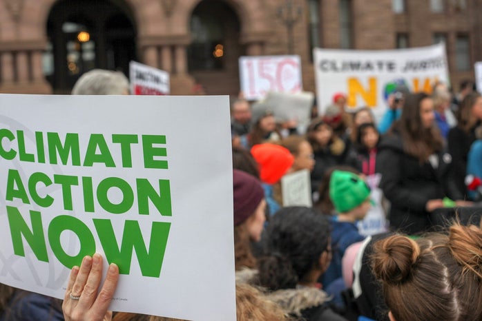protest sign that says "climate action now" in front of a crowd