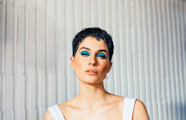 Girl with short hair and a white tank top wear blue eyeshadow