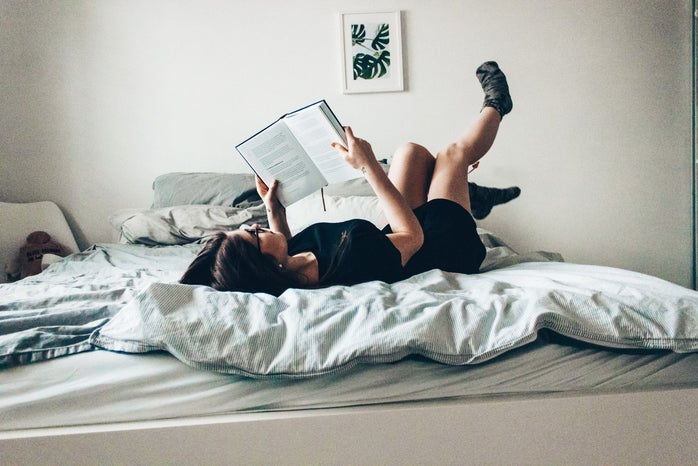Girl laying on bed reading book