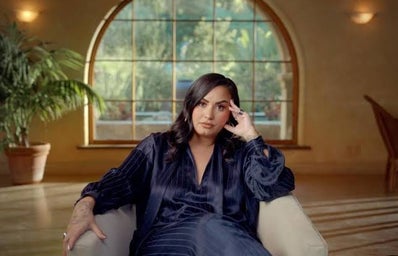 Demi Lovato sitting on a chair with a blue outfit
