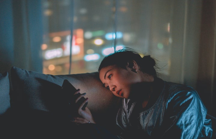 woman scrolling through phone late at night