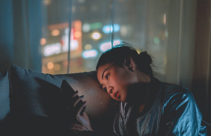 woman scrolling through phone late at night