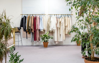 Clothing hangs on a rack with plants on the sides.