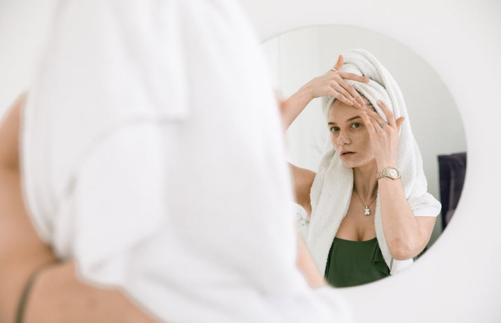 woman standing in front of a mirror applying cream