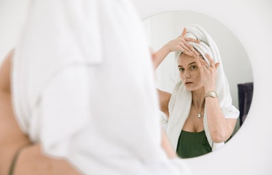 woman standing in front of a mirror applying cream
