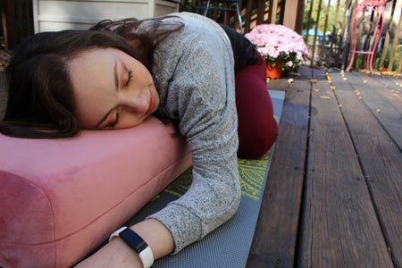 Camryn on a pink yoga bolster in Child's pose