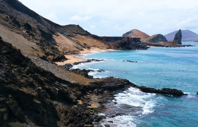 brown and green mountains beside body of water during daytime in galapagos islands, ecuador