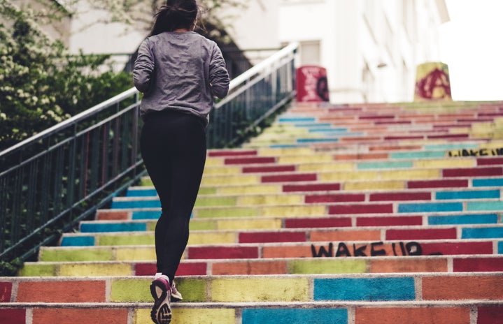 woman running up colorful stairs