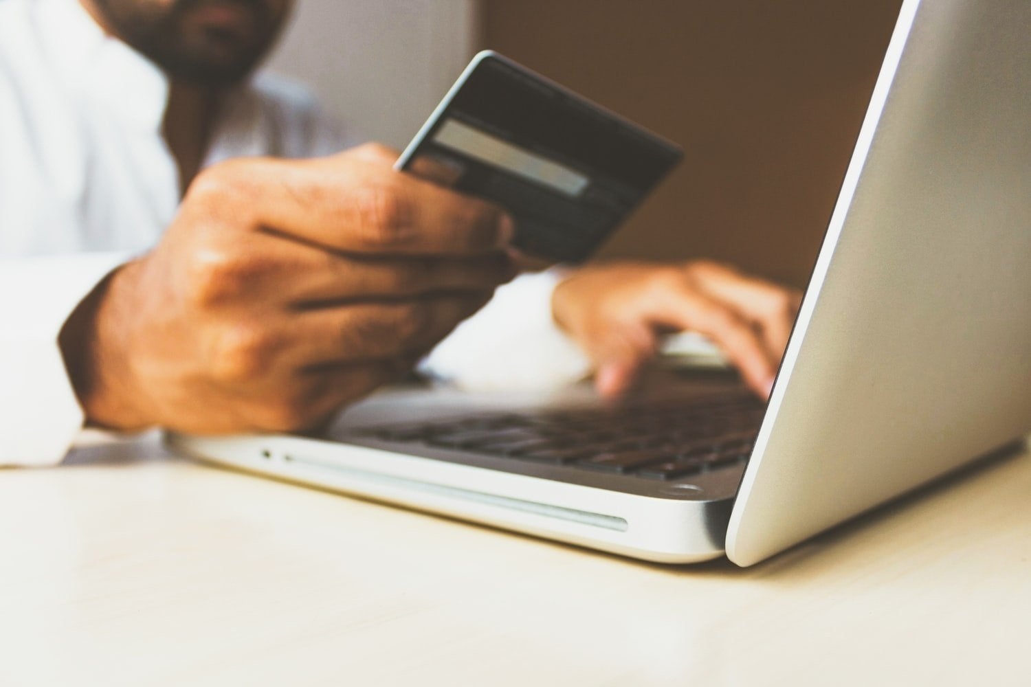 Person using laptop holding credit card